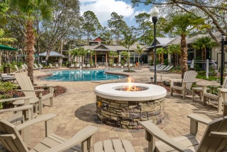 outdoor fire pit surrounded by chairs next to swimming pool