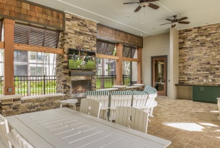 large covered patio with ceiling fans fireplace, tv and social sitting areas