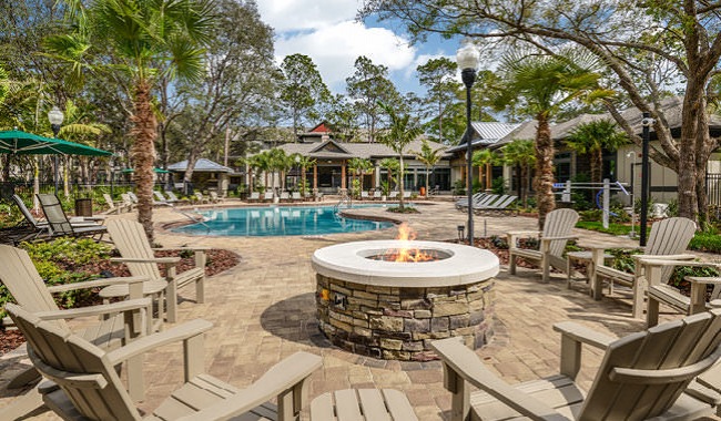 open fire place surrounded by lawn chairs near pool